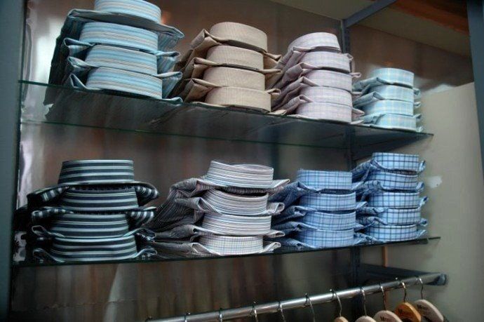 Folded dress shirts stacked on glass shelves at Mosher's — blues, whites, stripes and checks.