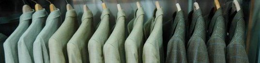 A rail of sport coats at Mosher's in soft greens and checks, shoulder to shoulder on wooden hangers.