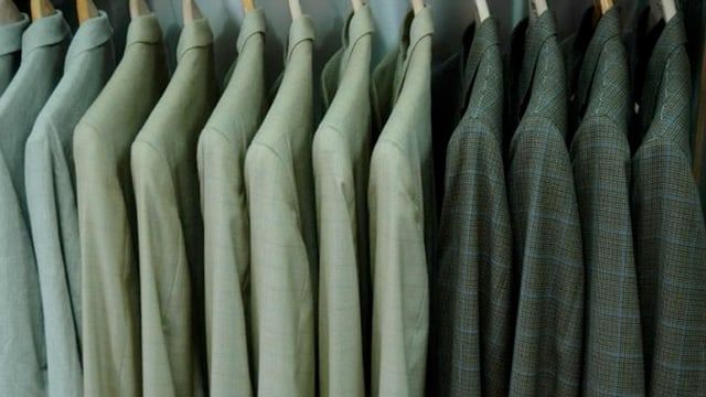 A frame from the store film: a rail of sport coats in soft green and check, shoulder to shoulder.