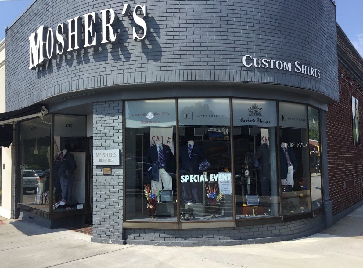 The Mosher's storefront: a curved corner of black glazed brick with MOSHER'S in white serif letters above the windows and CUSTOM SHIRTS along the side.